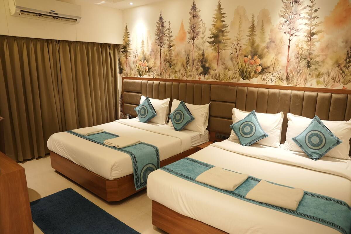 A hotel room with two beds, a large mural of trees, and a wooden headboard.