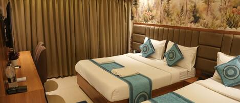 Habitación de hotel con dos camas, un escritorio, una silla, un ventanal con cortinas y un mural en la pared.
