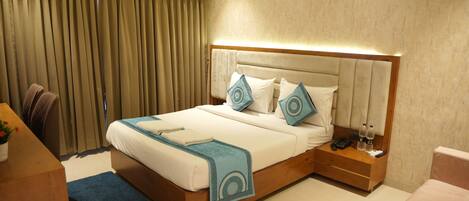 Una habitación de hotel con cama, mesita de noche y escritorio con silla.