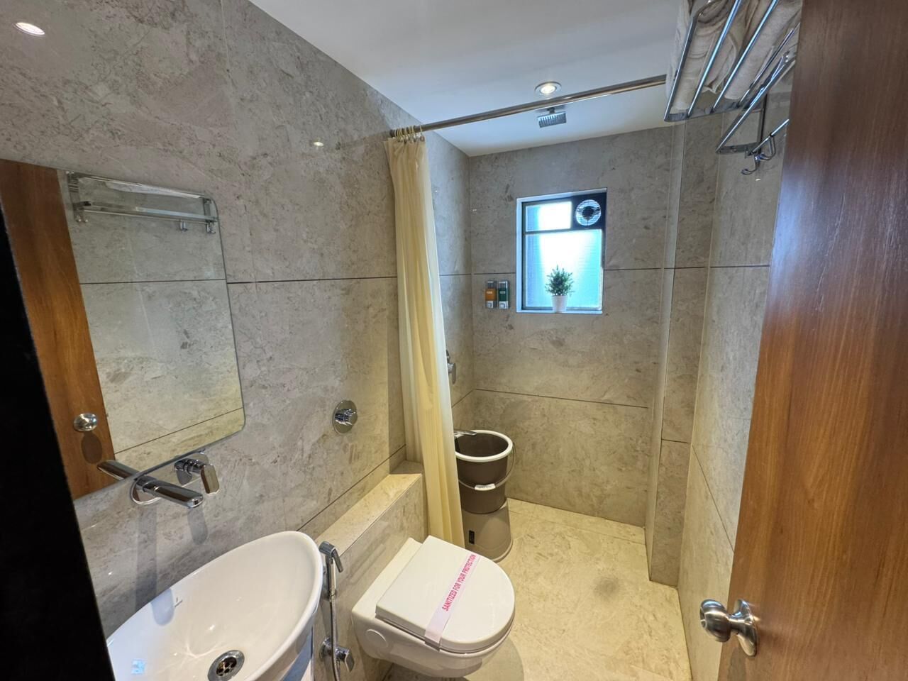 A modern bathroom with a marble floor, a white sink, a toilet, and a shower area.