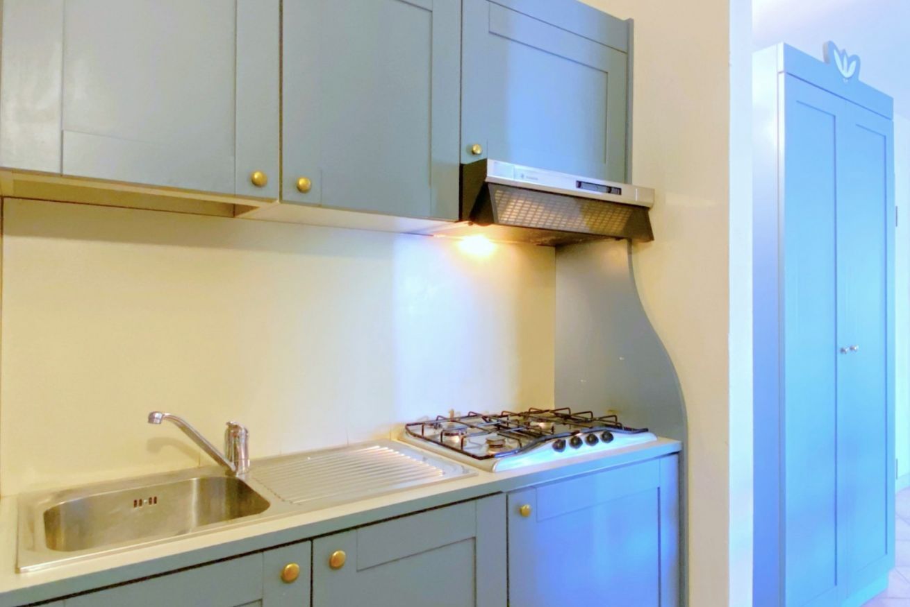 A kitchen with light blue cabinets, a stainless steel sink, and a gas stove.