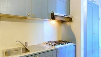 A kitchen with light blue cabinets, a stainless steel sink, and a gas stove.