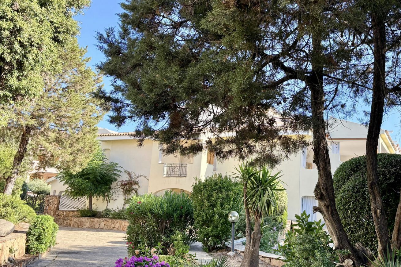A garden pathway leading to a building with a stone wall and various plants.