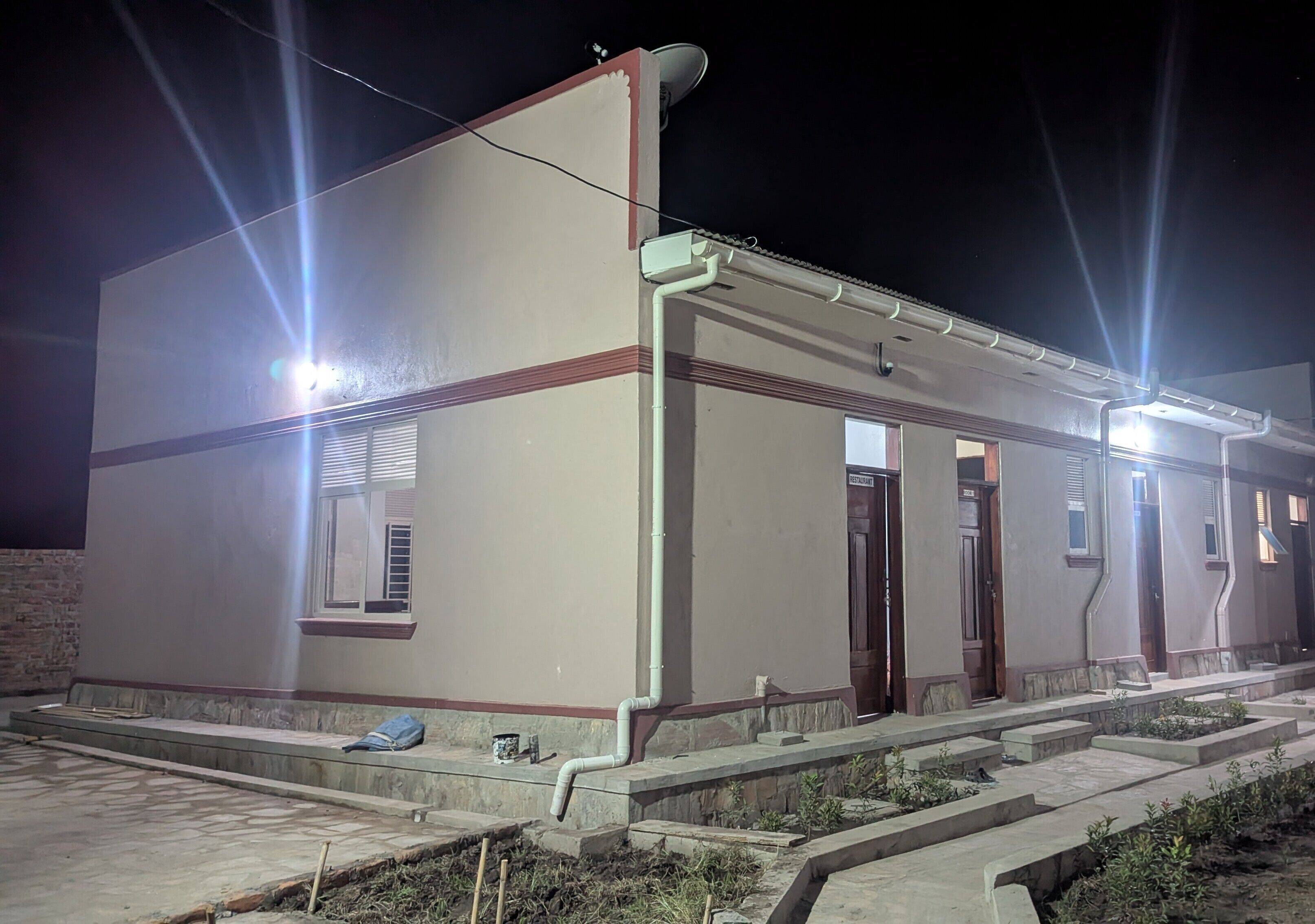 A building with a flat roof, a satellite dish, and a series of doors and windows.