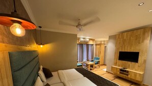 A modern hotel room with a large bed, a TV mounted on the wall, and a ceiling fan. - Ceylon Bake House Woodland Junction (Kanayannur)