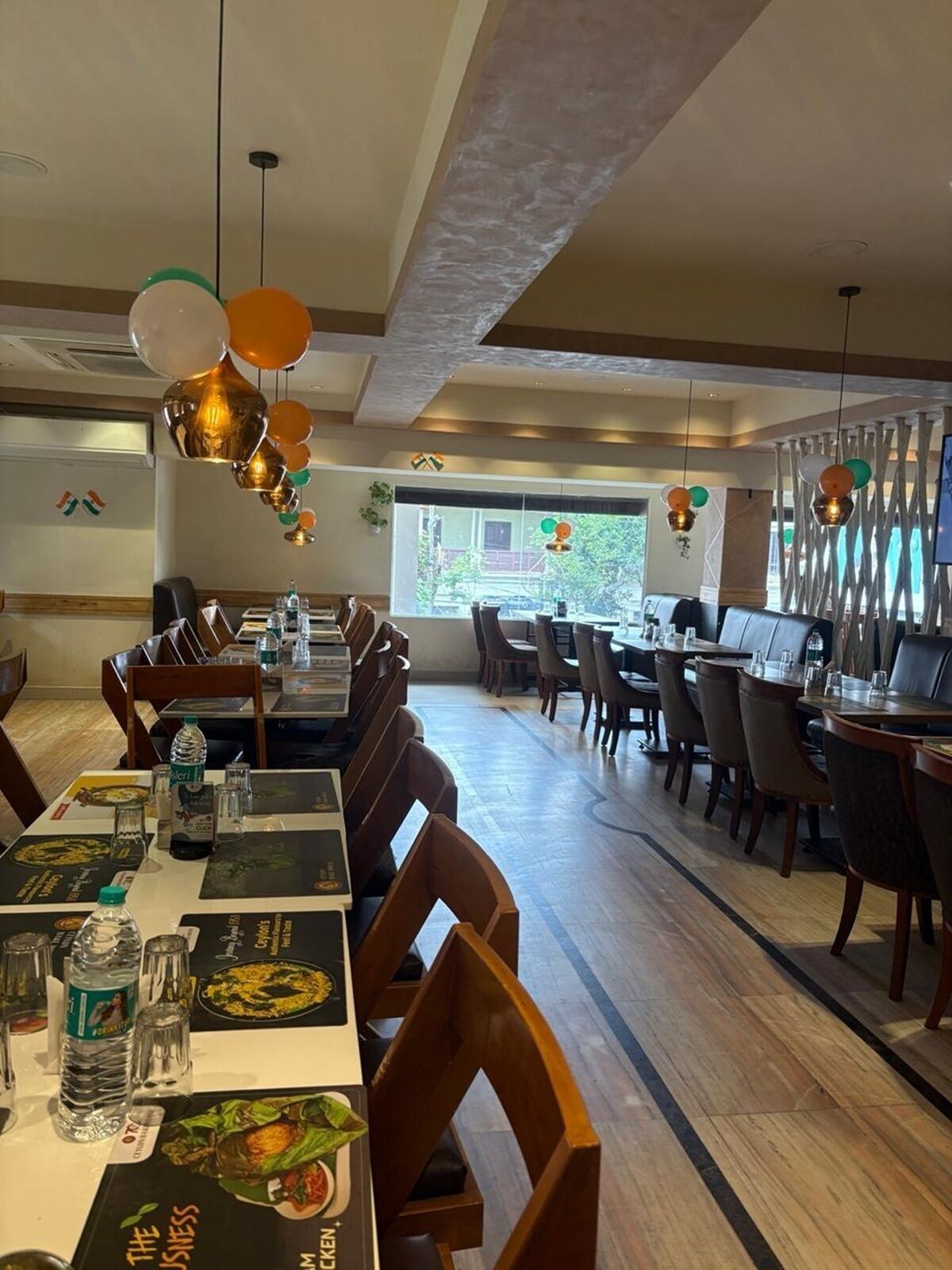 A restaurant with wooden tables and chairs, hanging decorations, and a view of the outdoors.