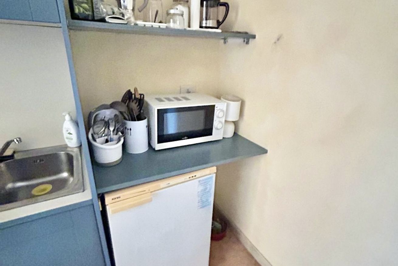 Une cuisine de taille réduite équipée d’un four à micro-ondes, d’un évier et d’un petit réfrigérateur.