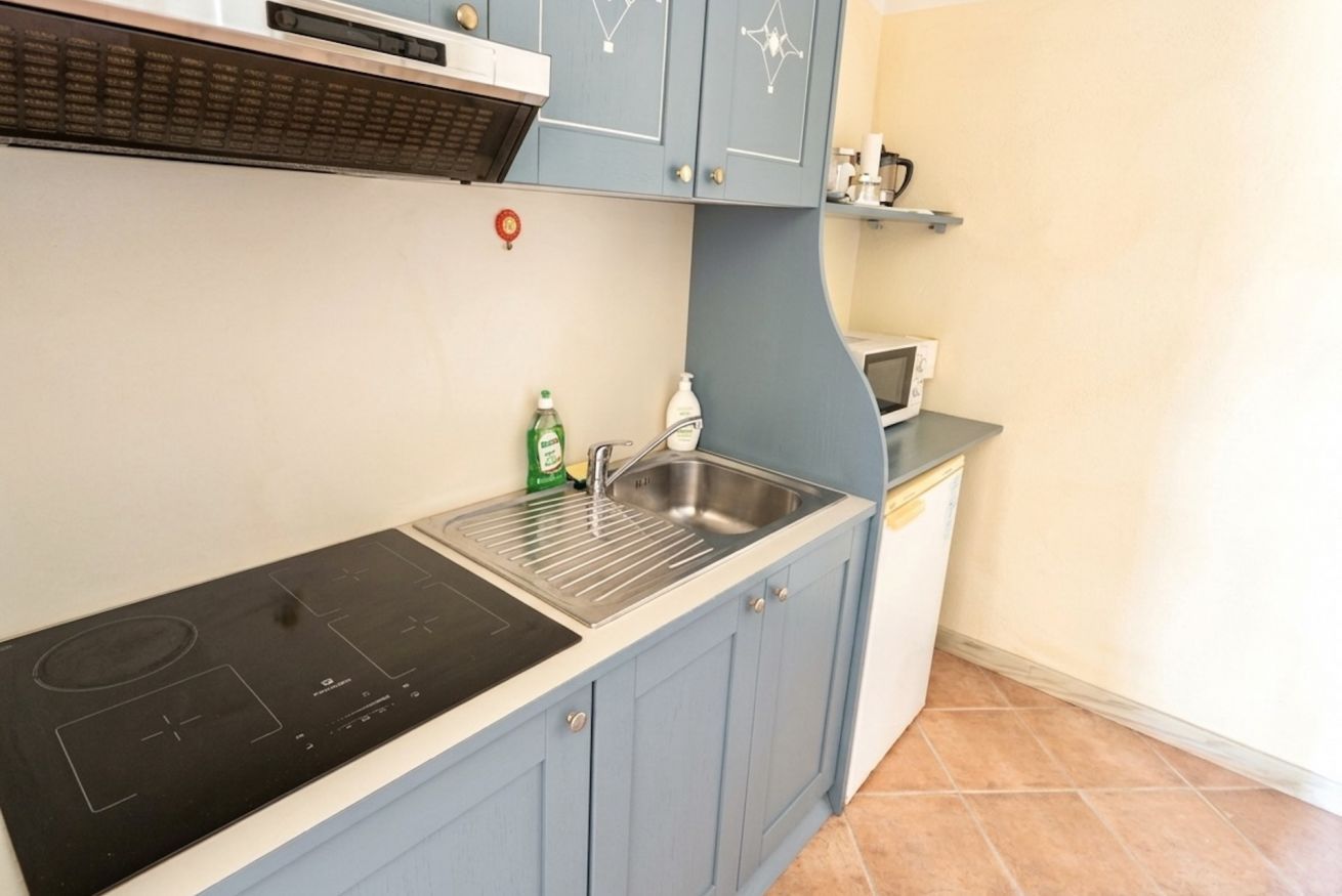 Una cocina con estufa integrada, pileta y alacenas.