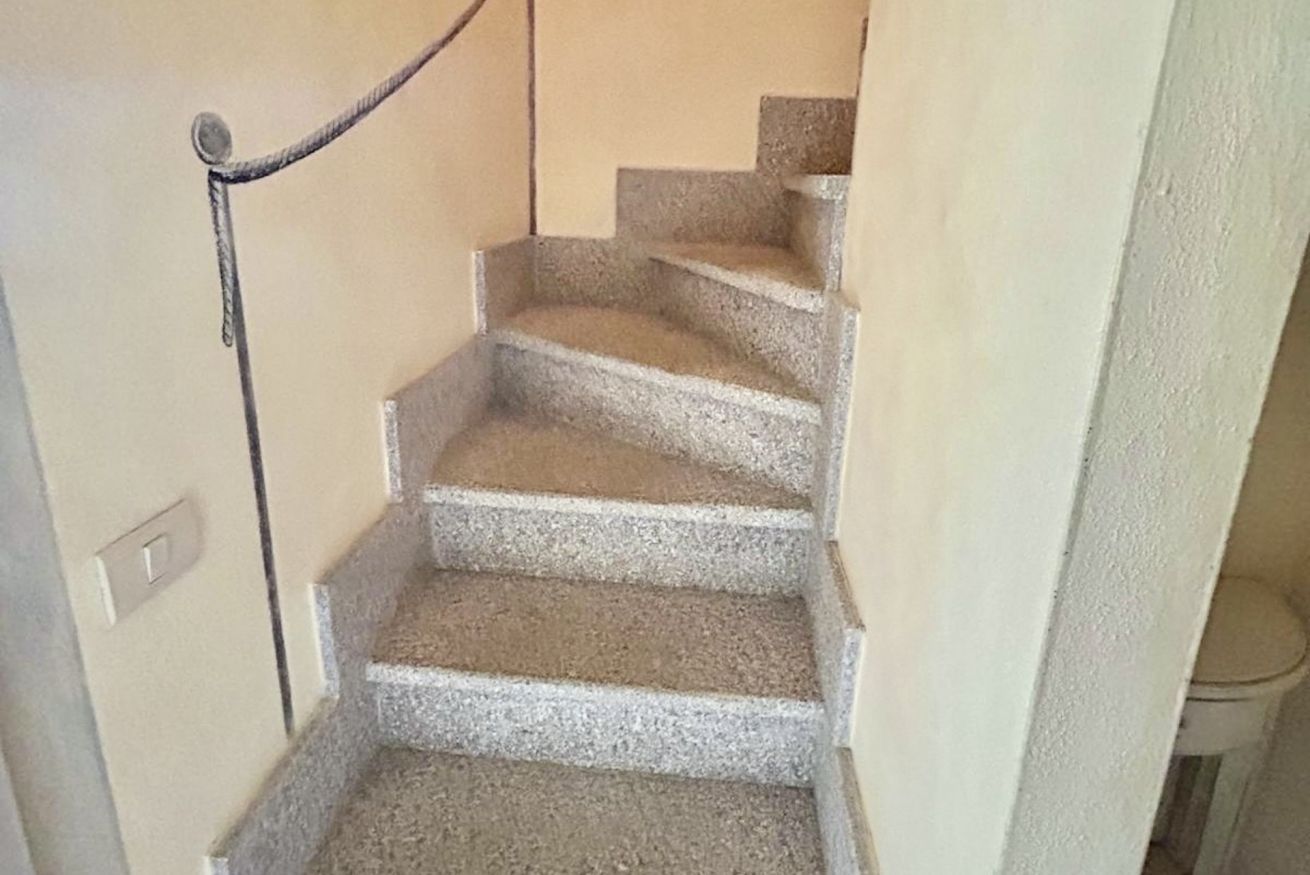 A staircase with a handrail and a light switch on the wall.