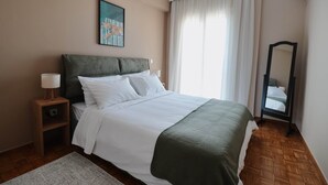 Une chambre à coucher bien rangée, avec un lit, des lampes de chevet, un miroir et un tableau accroché au mur.