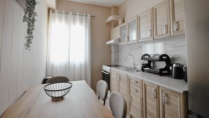 Une cuisine de taille réduite comprenant une table à manger, des chaises, un évier et un réfrigérateur.