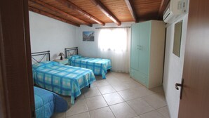 Une chambre avec deux lits, une armoire et une fenêtre avec des rideaux.