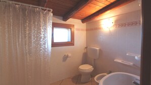 Une salle de bain avec un rideau de douche, des toilettes et une baignoire.