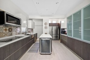 A modern kitchen with a central island, stainless steel appliances, and a patterned backsplash. - Enchanted Hideaway with Private Pool (Puerto Rico)