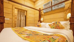 Een bed met een kleurrijke quilt, houten wanden en een deur met gordijn.