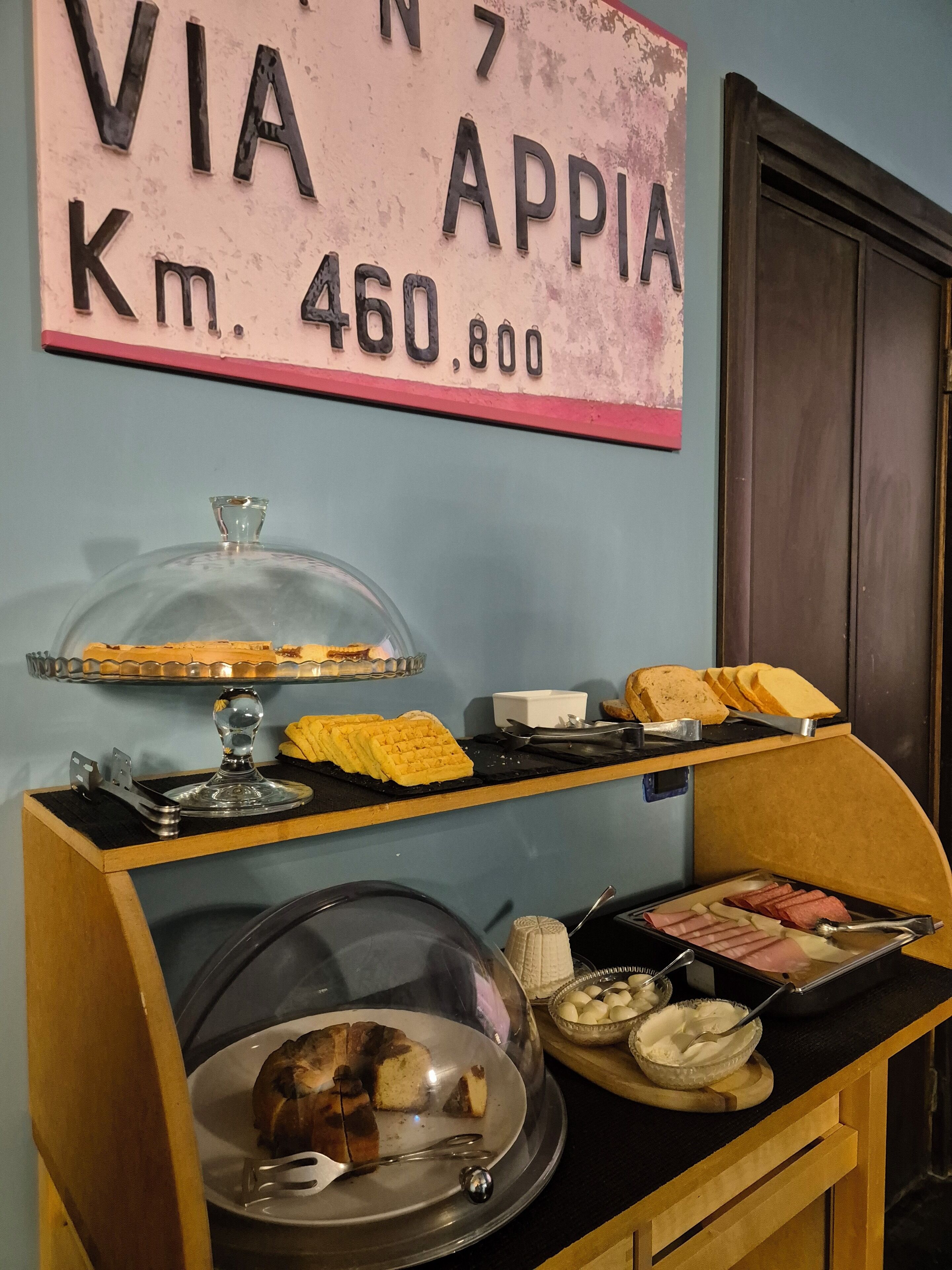 Buffet de café da manhã com diversos alimentos e uma placa indicando a distância até Appia.