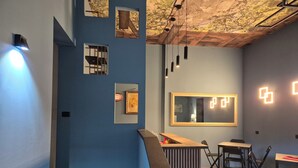 A modern interior with a blue wall, a wooden counter, and a seating area with chairs and tables.