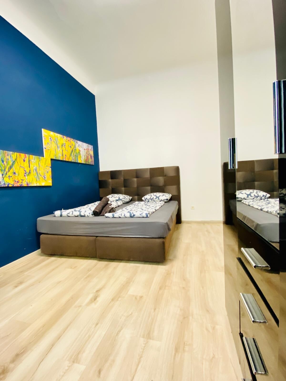 Ein modernes Schlafzimmer mit Bett, Fernseher und Kunstwerken an der Wand.
