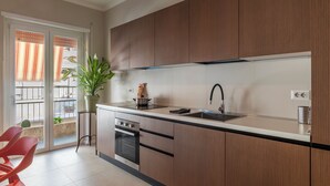 A modern kitchen with wooden cabinets, a stainless steel sink, and a potted plant. - ST PETER POSTCARD VIEW PENTHOUSE (Roma)