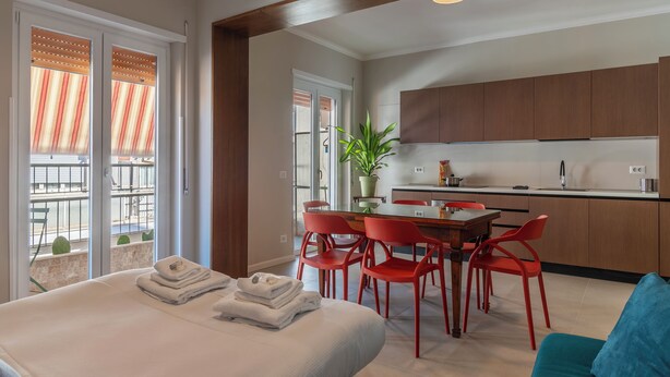 A modern hotel room with a balcony, a dining area with red chairs, and a kitchen with wooden cabinets. - ST PETER POSTCARD VIEW PENTHOUSE (Roma)