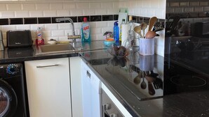 Una cocina moderna con armarios blancos, encimera negra y electrodomésticos de acero inoxidable, incluyendo lavavajillas, horno y lavadora.