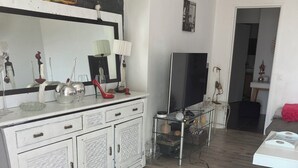 Una sala de estar moderna con un mueble blanco, un televisor de pantalla plana y una mesa de centro de vidrio.