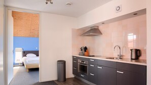 Et kompakt køkken med moderne hårde hvidevarer, indbygget ovn og stålvask.