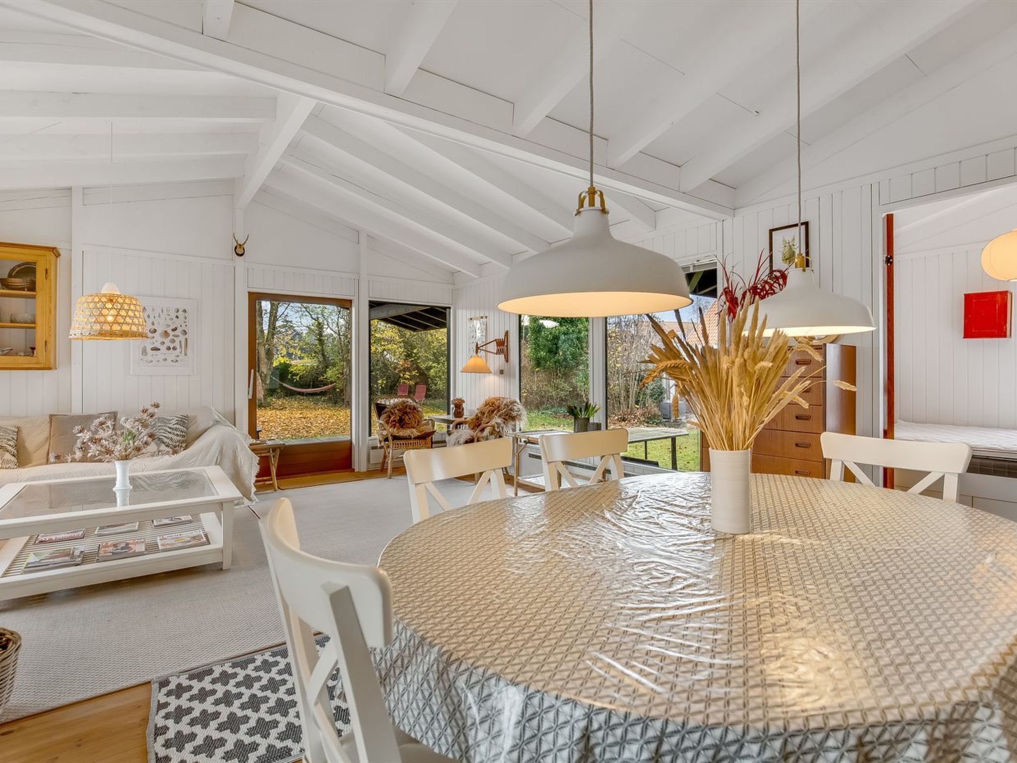 A modern interior with a round table, white furniture, and a view of the outdoors.