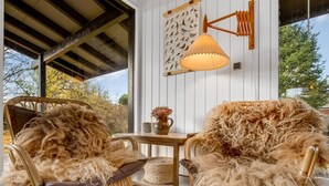 Een gezellige zithoek met twee stoelen bekleed met zachte vacht, een tafel met een vaas en een wandlamp.