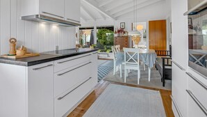 Een moderne keuken met witte kastjes, een zwart aanrecht en een eethoek met een tafel en stoelen.