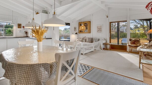 Een ruime woonkamer met een hoge plafond, witte wanden en een groot raam met uitzicht op het omliggende landschap.
