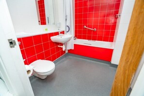 Ein Badezimmer mit Toilette, roten Fliesen, einem Waschbecken und einer Badewanne.