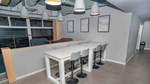 A modern kitchen area with a white countertop, bar stools, pendant lights, and framed artwork on the wall. - 2 Budget En-Suite Rooms with Shared Kitchen (Coventry)
