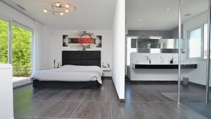 Une chambre moderne avec un grand lit, une table de chevet et une œuvre d’art accrochée au mur.