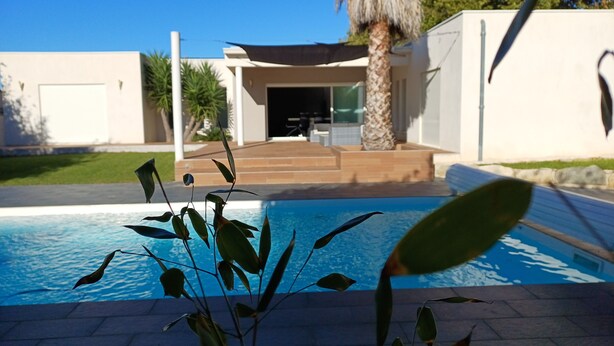 Une maison moderne dotée d’une piscine, d’un patio et d’un escalier menant à l’entrée.
