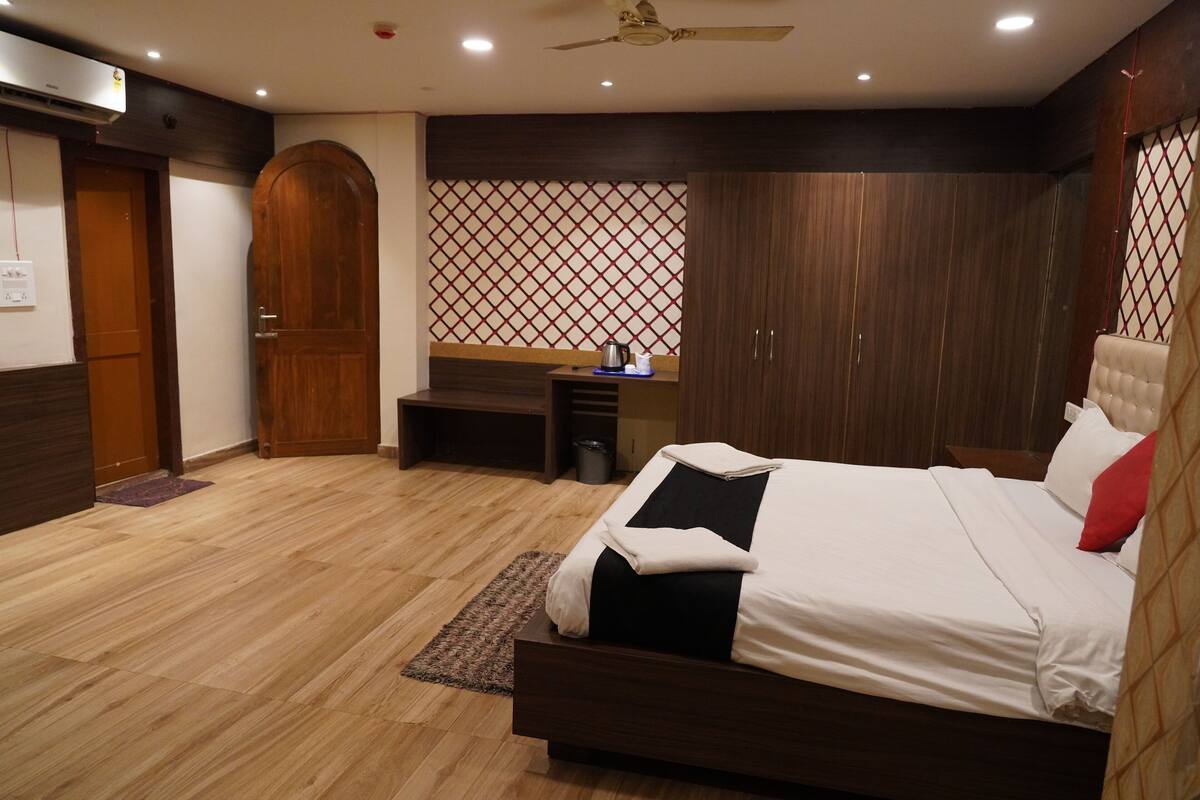 A bedroom with a bed, wooden wardrobe, and a desk with a chair.