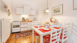Una cocina con armarios blancos, una mesa de comedor con individuales rojos y sillas.