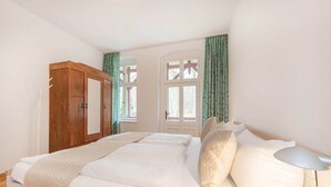 Un dormitorio con cama, armario, ventana con cortinas y puerta.