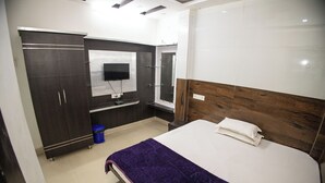 A bedroom with a bed, a wardrobe, a TV, and a mirror. - Sri Residency (Ujjain)