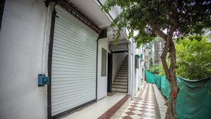 A corridor with a closed shutter door, a staircase, and a checkered floor. - Sri Residency (Ujjain)
