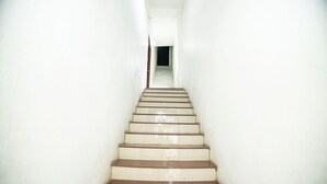A narrow, white-walled stairway leading to a dark doorway at the top. - Sri Residency (Ujjain)