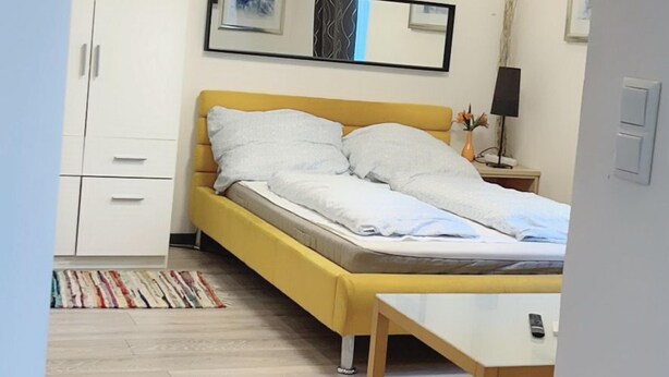 Ein modernes Schlafzimmer mit Bett, Nachttisch, Lampe und Kleiderschrank.