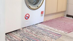 Eine kleine Küche mit Waschmaschine, Mikrowelle und Holzschränken.