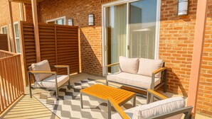 A balcony with a sofa, chairs, and a table. - Downtown Loft • Balcony • King Bed • Stylish Stay (Motgomery)