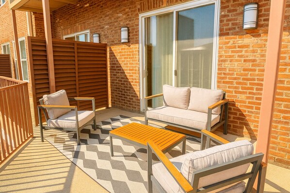 A balcony with a sofa, chairs, and a table.