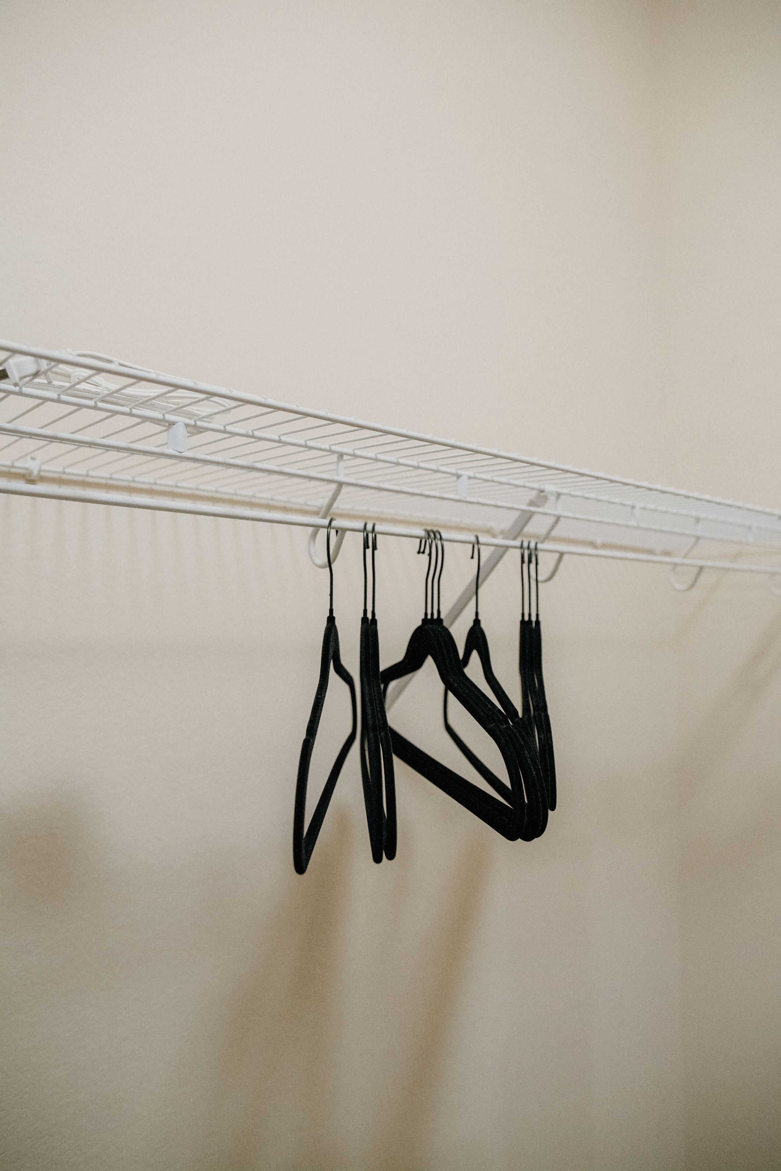 A white metal drying rack with several black hangers hanging from it.