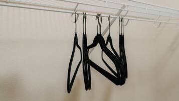 A white metal drying rack with several black hangers hanging from it.
