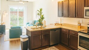 A modern kitchen with dark wood cabinets, stainless steel appliances, and a large island. - Downtown Loft • Balcony • King Bed • Stylish Stay (Motgomery)