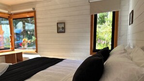 Un dormitorio con cama, ventana y un cuadro en la pared.