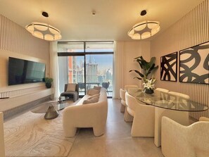 A modern living room with a sofa set, a glass coffee table, and a flat-screen TV mounted on the wall. - Artistic 2Bedroom with Skyline Khalifa View (Business Bay)